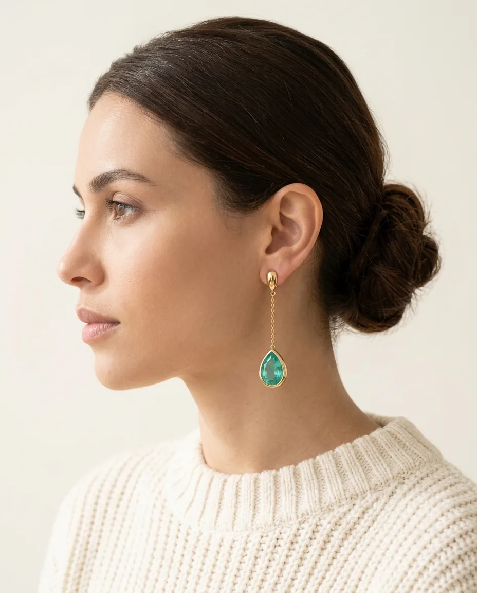 Perfil de mulher usando brinco de ouro com gota verde-água